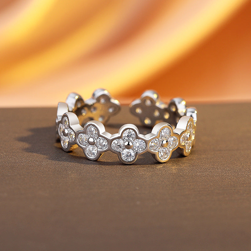 Silver ring with floral design and embedded stones on a brown surface with orange background