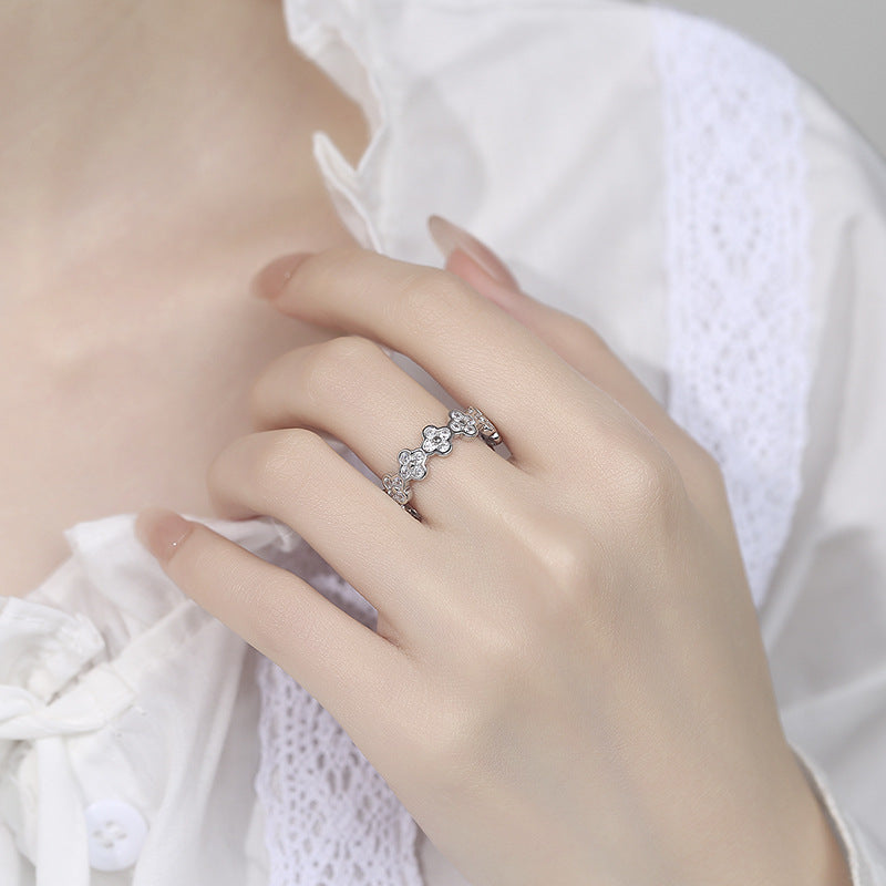 Hand wearing a silver ring with floral design on a white background