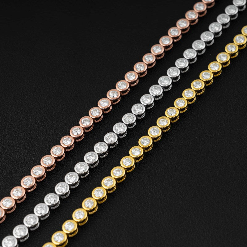 Three tennis-style chains with round bezel-set clear stones in rose gold, silver, and yellow gold, arranged diagonally on a black background.