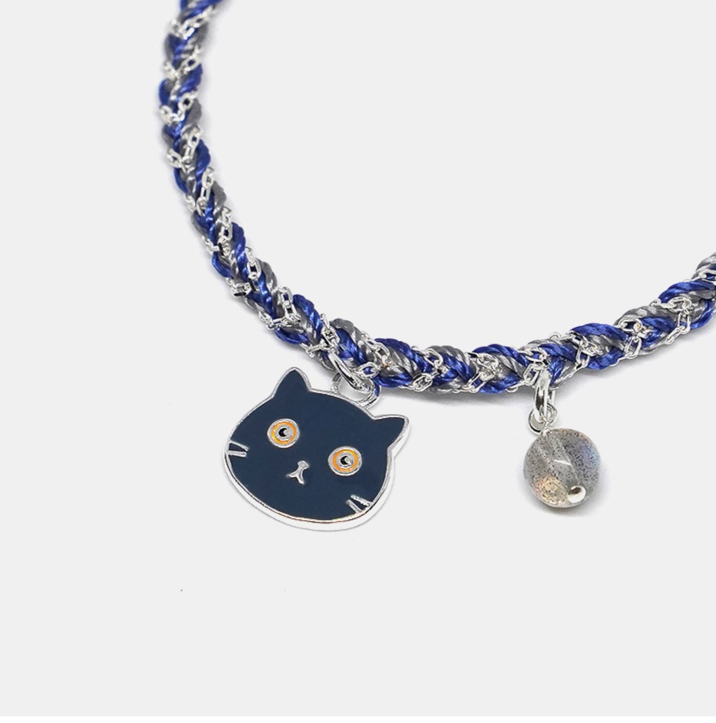 Bracelet with a cat charm and blue and silver braided design on a white background