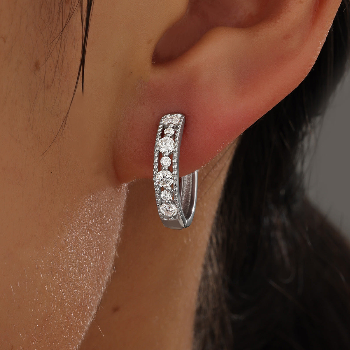Multiple hoop sizes worn together. Alt: “Stacked Round Hoops: Pavé Moissanite Earrings.”