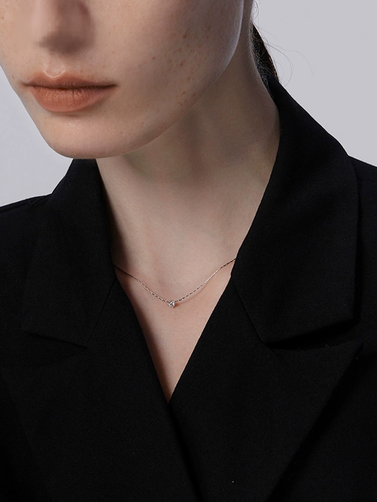 Person wearing a delicate necklace with a plain background