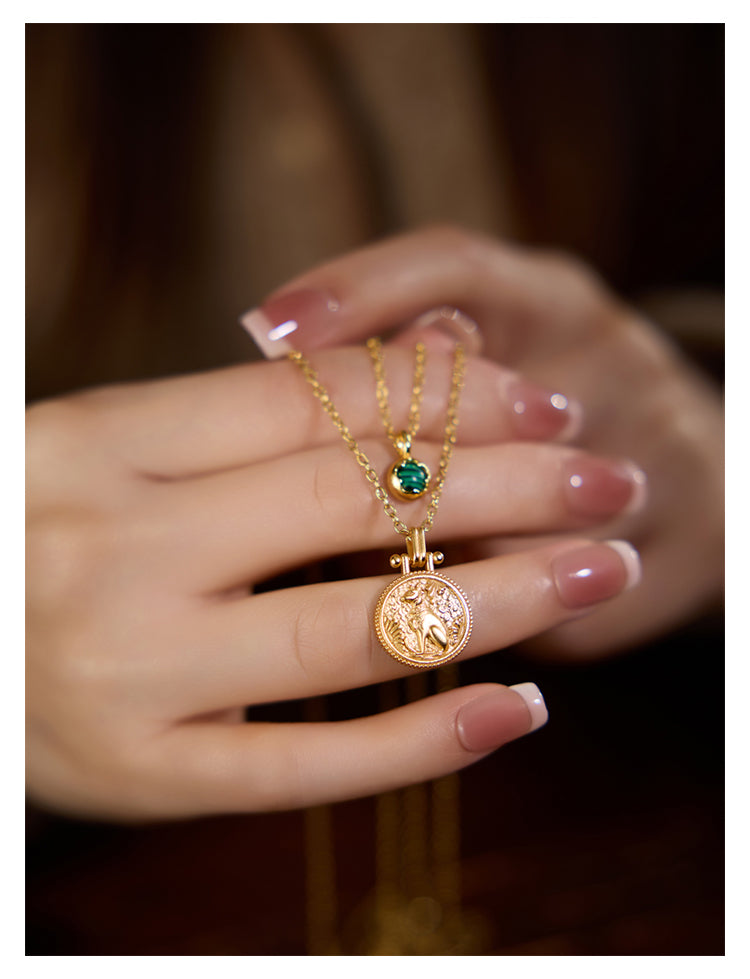 Gold necklaces with pendants on a hand against a blurred background