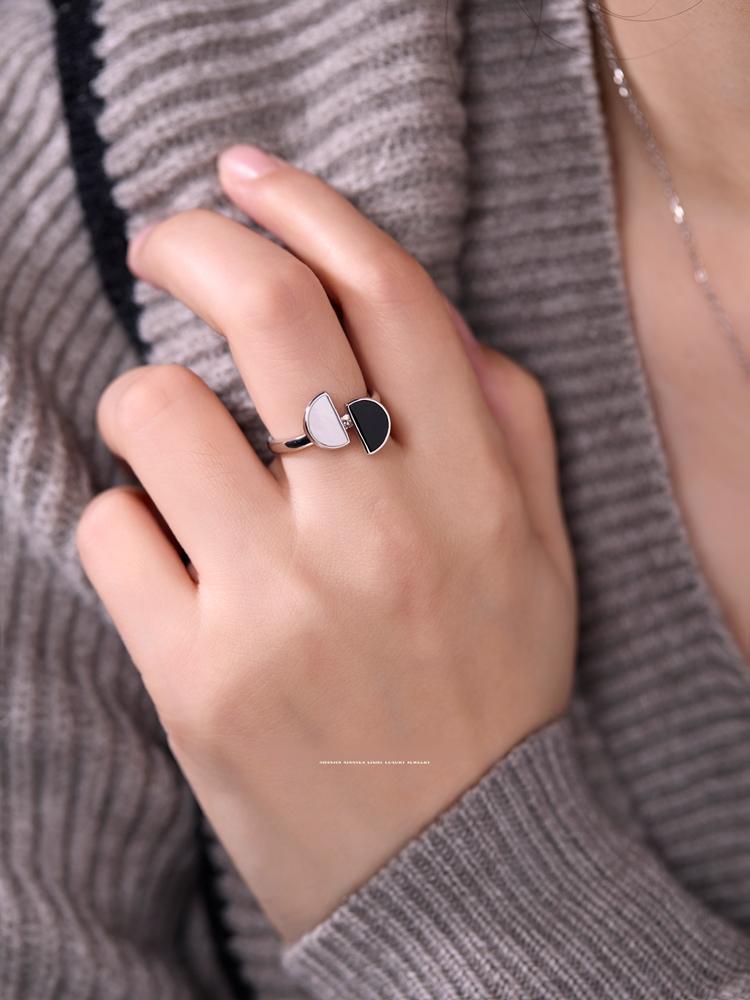 Hand wearing a silver ring with a heart design on a gray textured background