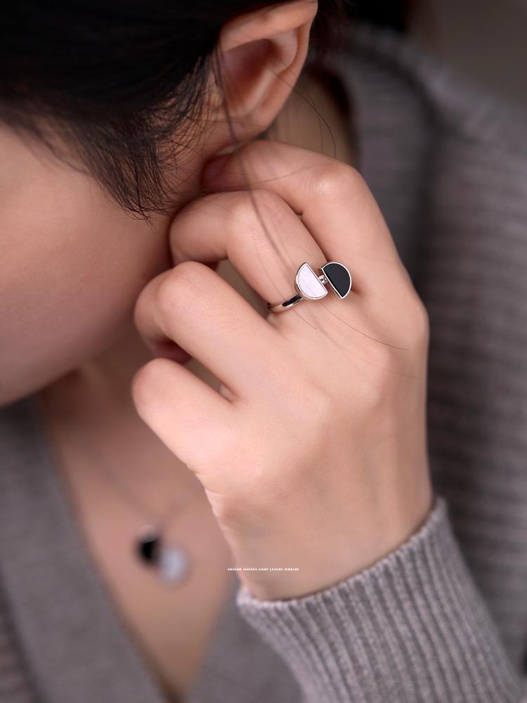 Close-up of a hand wearing a ring with a unique design, touching the ear.