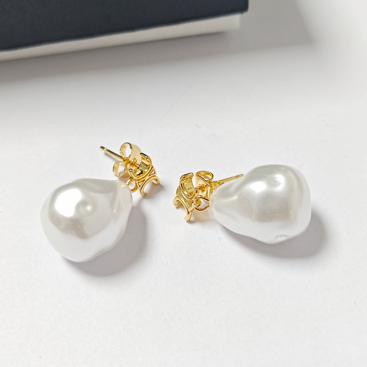 A pair of baroque pearl stud earrings with gold post backings, displayed on a clean white surface.