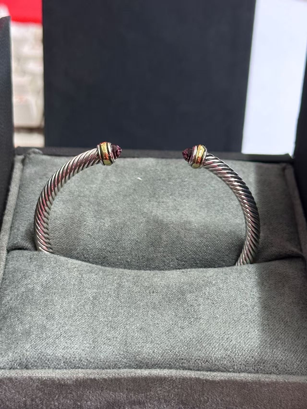 Silver bracelet with gold accents on a gray cushioned surface
