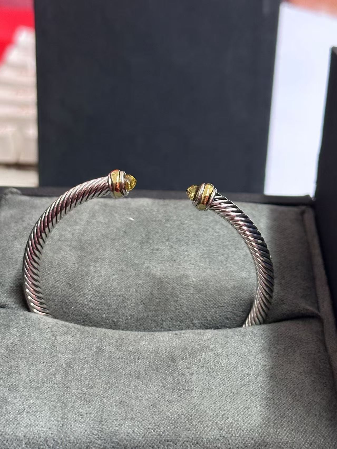 Silver bracelet with gold accents on a gray surface