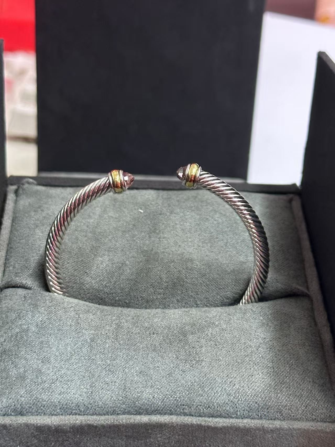 Silver bracelet with gold accents on a gray cushioned surface