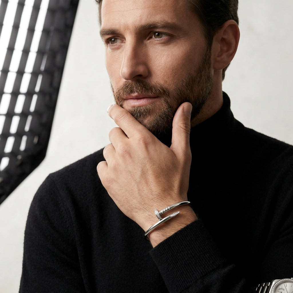 Man wearing a black sweater with a silver bracelet, posing thoughtfully.