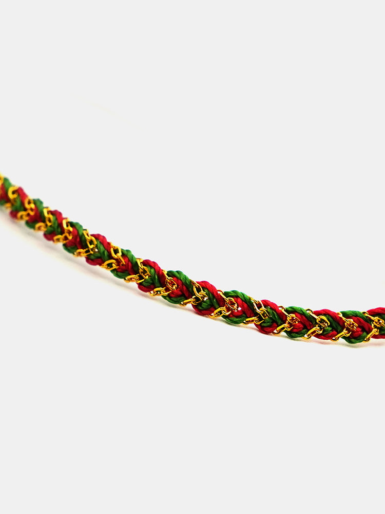 Bracelet with red, green, and gold braided pattern on a white background