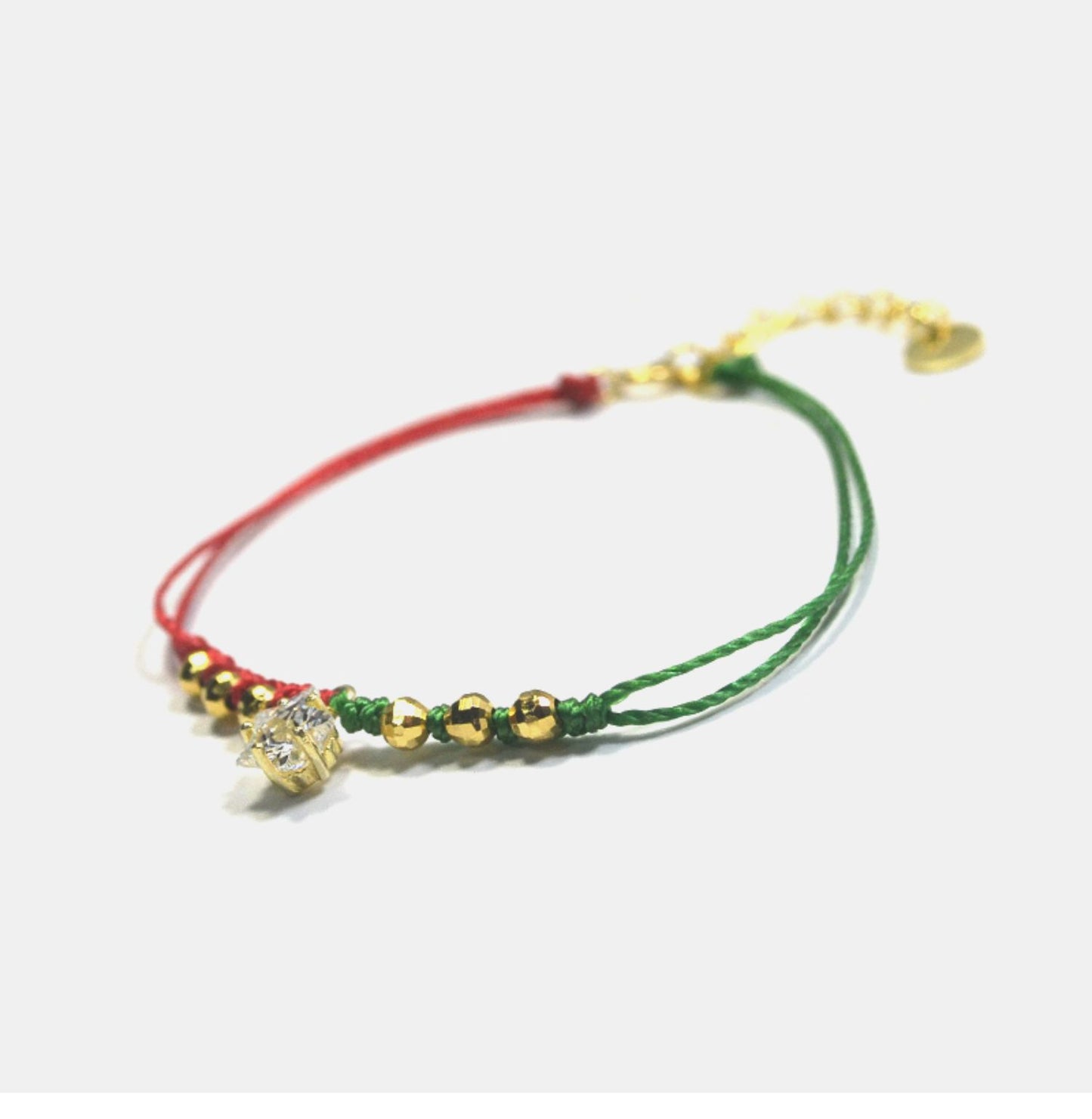 Bracelet with green and red strings and gold beads on a white background