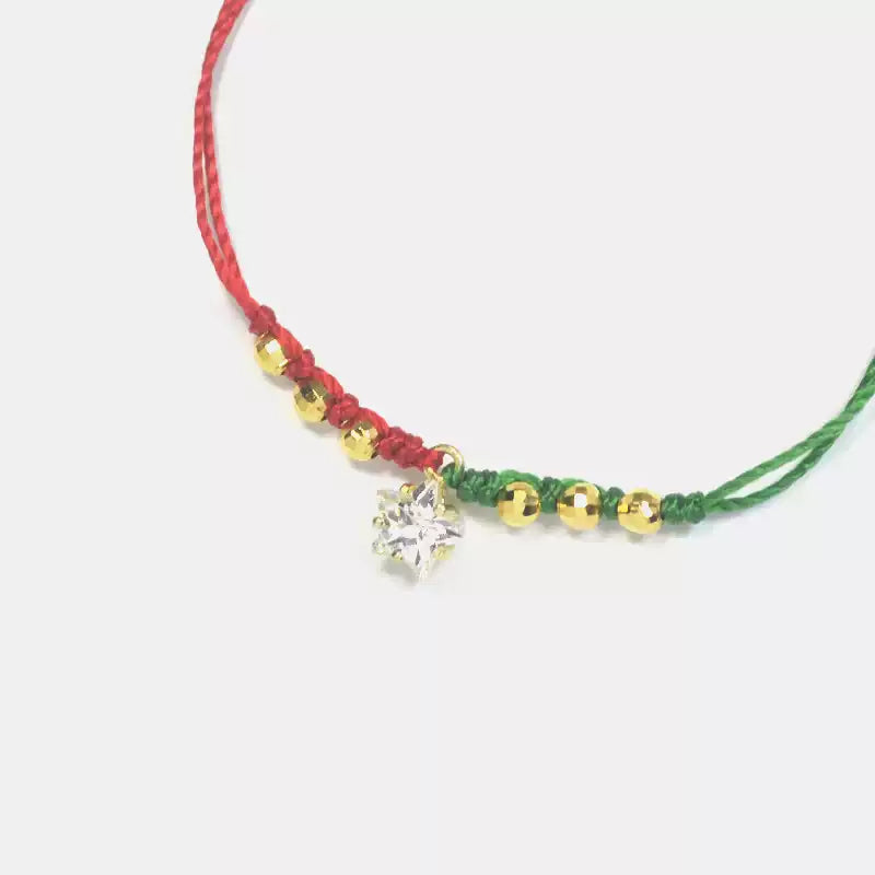Bracelet with red, green, and gold beads and a clear crystal charm on a white background