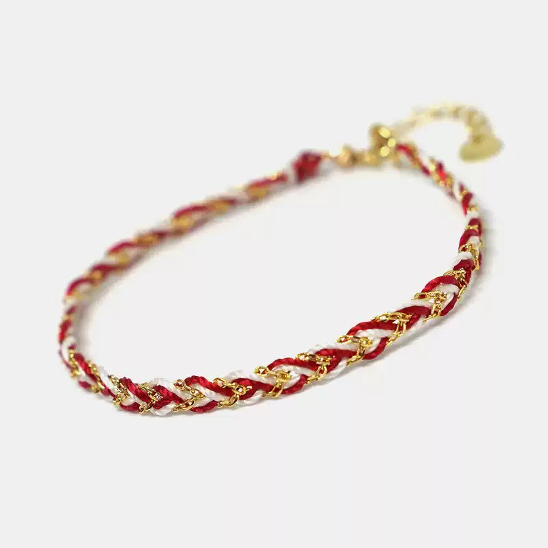 Bracelet with red, white, and gold braided design on a light background