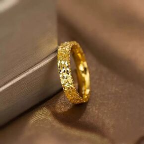 Gold ring with intricate design on a textured surface