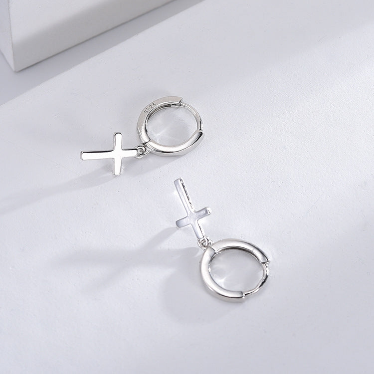 Silver hoop earrings with cross designs on a light gray background