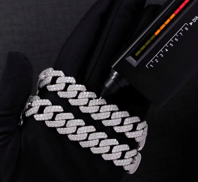Silver chain bracelet on a black background with a scale for size reference.
