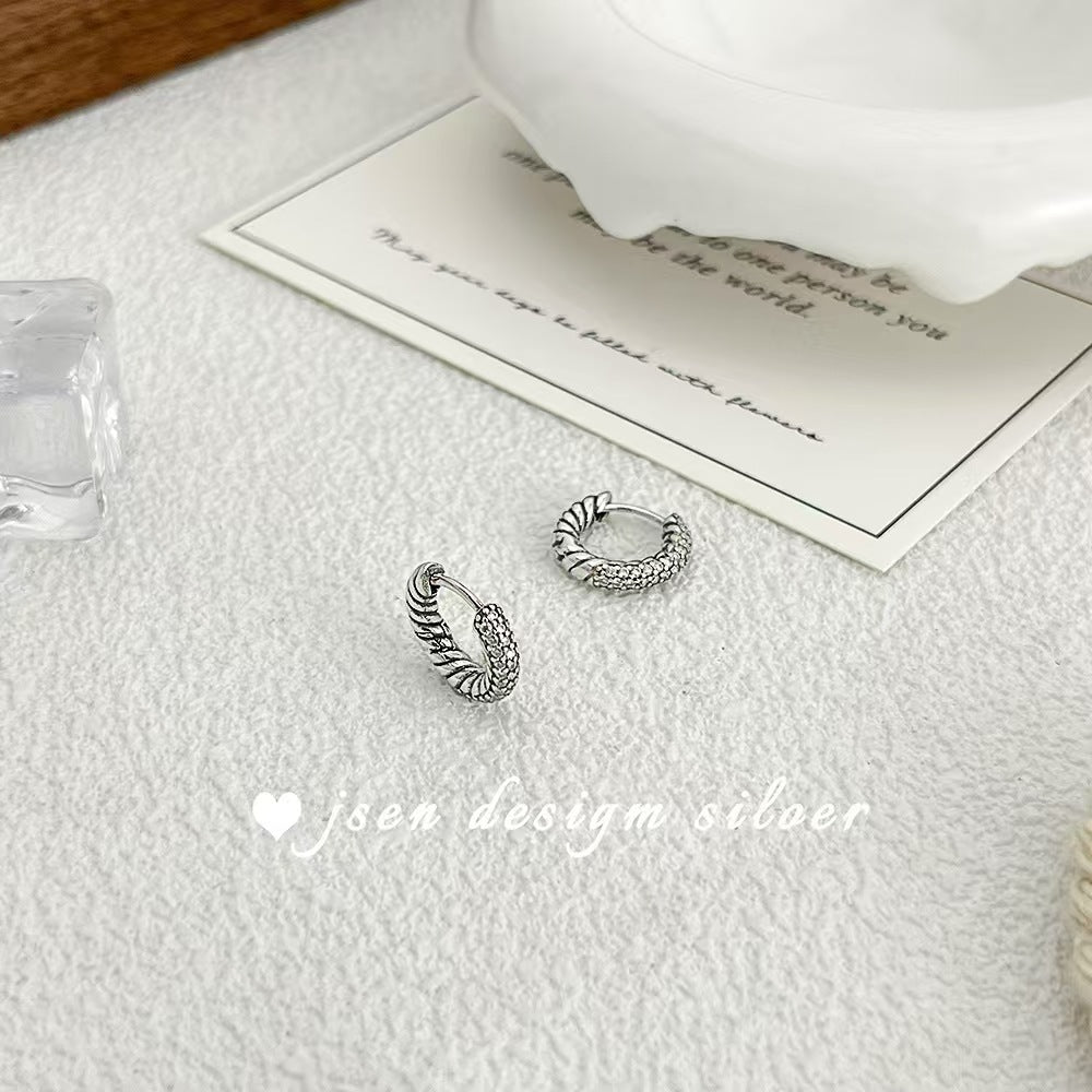 Silver hoop earrings on a textured surface with a card in the background, featuring 'jsew design silver' branding.
