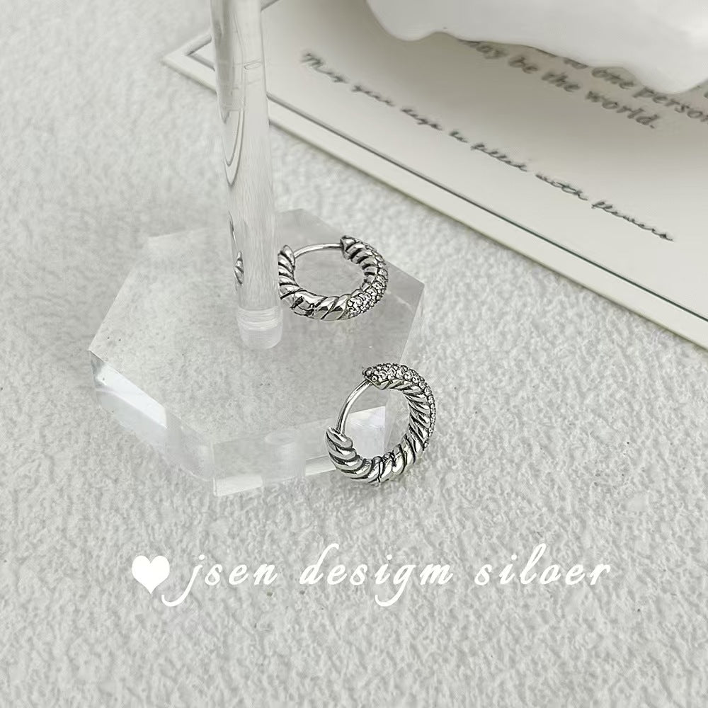 Silver hoop earrings on a clear stand with a soft background