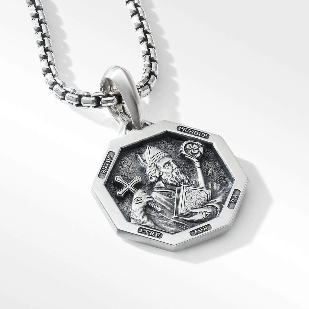 Silver pendant with intricate design on a white background