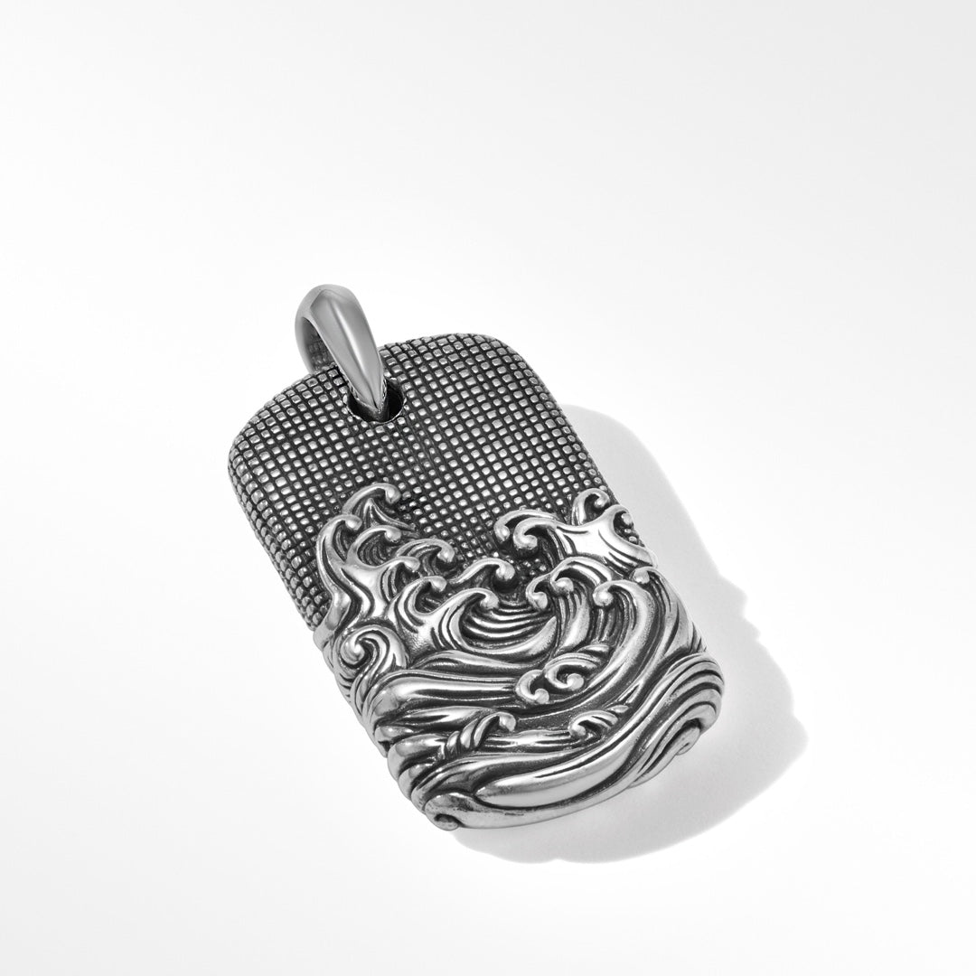 Silver pendant with intricate design on a white background