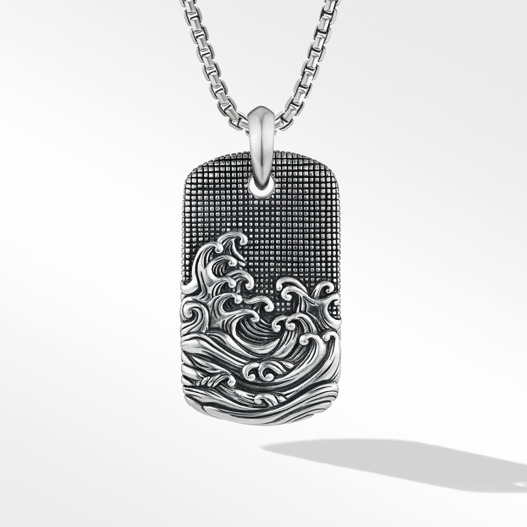 Silver dog tag pendant with wave design on a white background