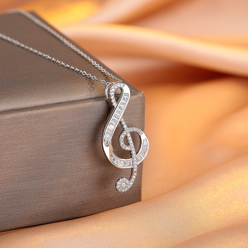 Silver music note pendant on a brown box with a soft orange background