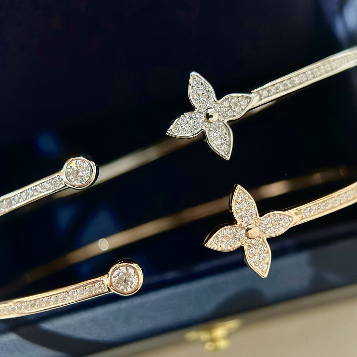 Gold bracelets with butterfly designs on a dark background