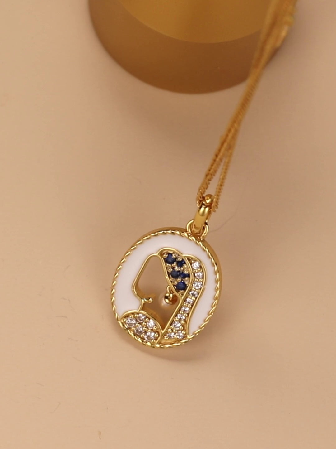 Gold necklace with a heart-shaped pendant on a beige background
