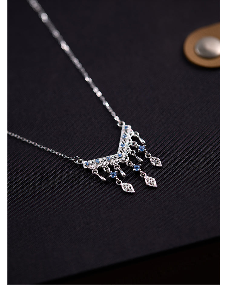 Silver necklace with dangling charms on a dark background