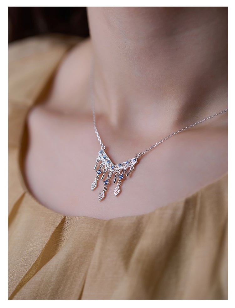 Necklace with a delicate design worn by a person against a neutral background