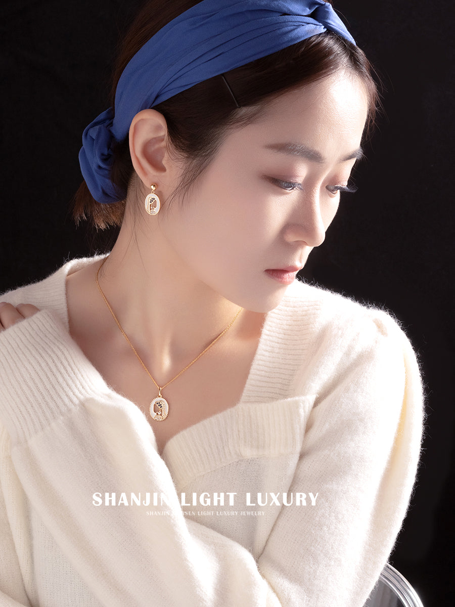 Woman wearing a blue headband and white sweater with jewelry, against a black background.