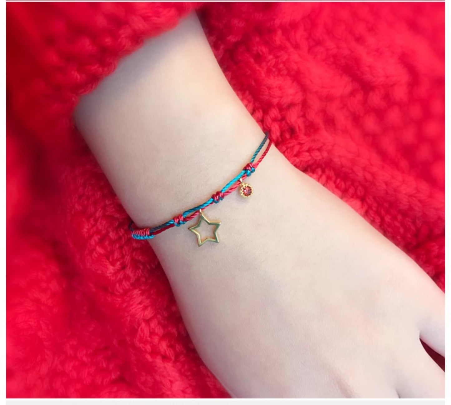 Bracelet with a star charm on a wrist against a red background