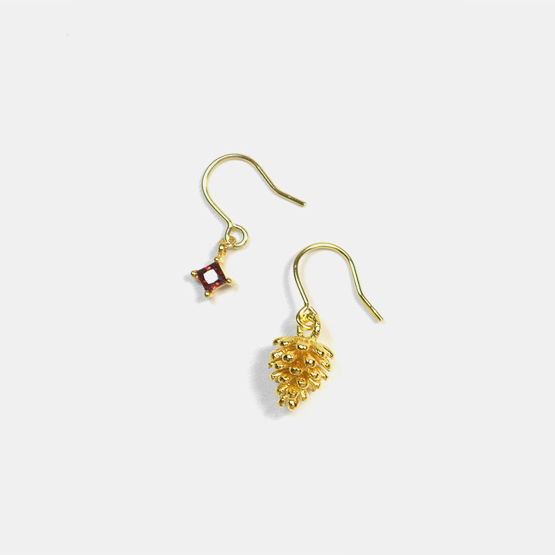 Gold earrings with a small red gemstone on a white background