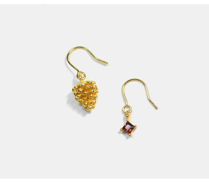 Two gold earrings with gemstones on a white background