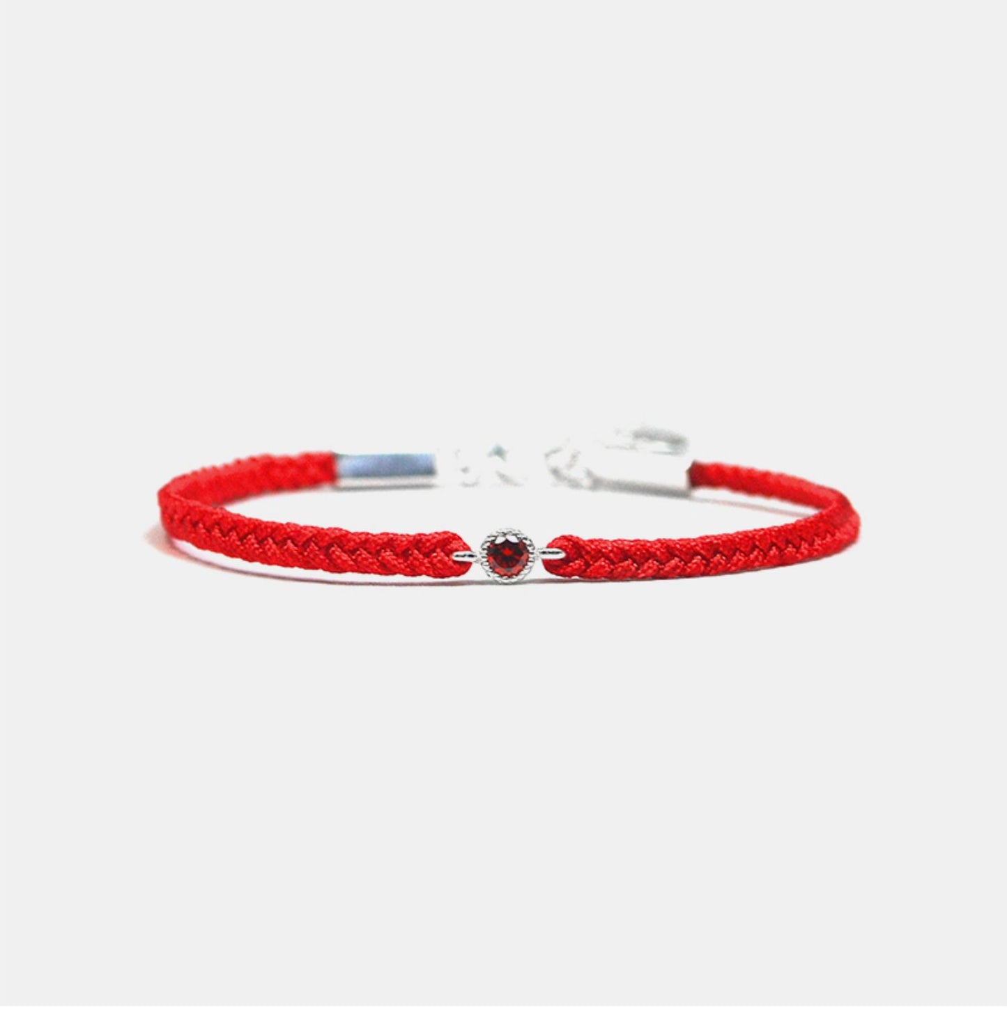 Red braided bracelet with a small round red gemstone on a white background