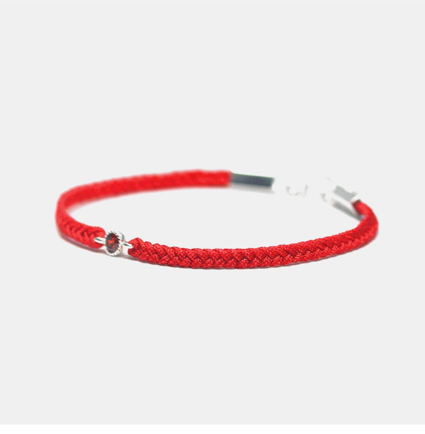 Red braided bracelet with a silver clasp on a white background