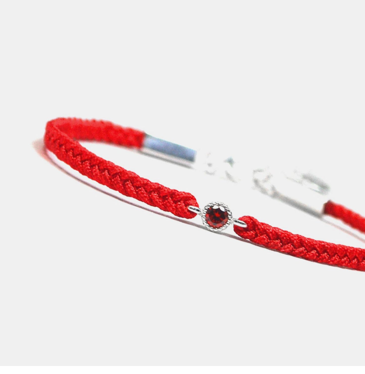 Red braided bracelet with a silver clasp on a white background