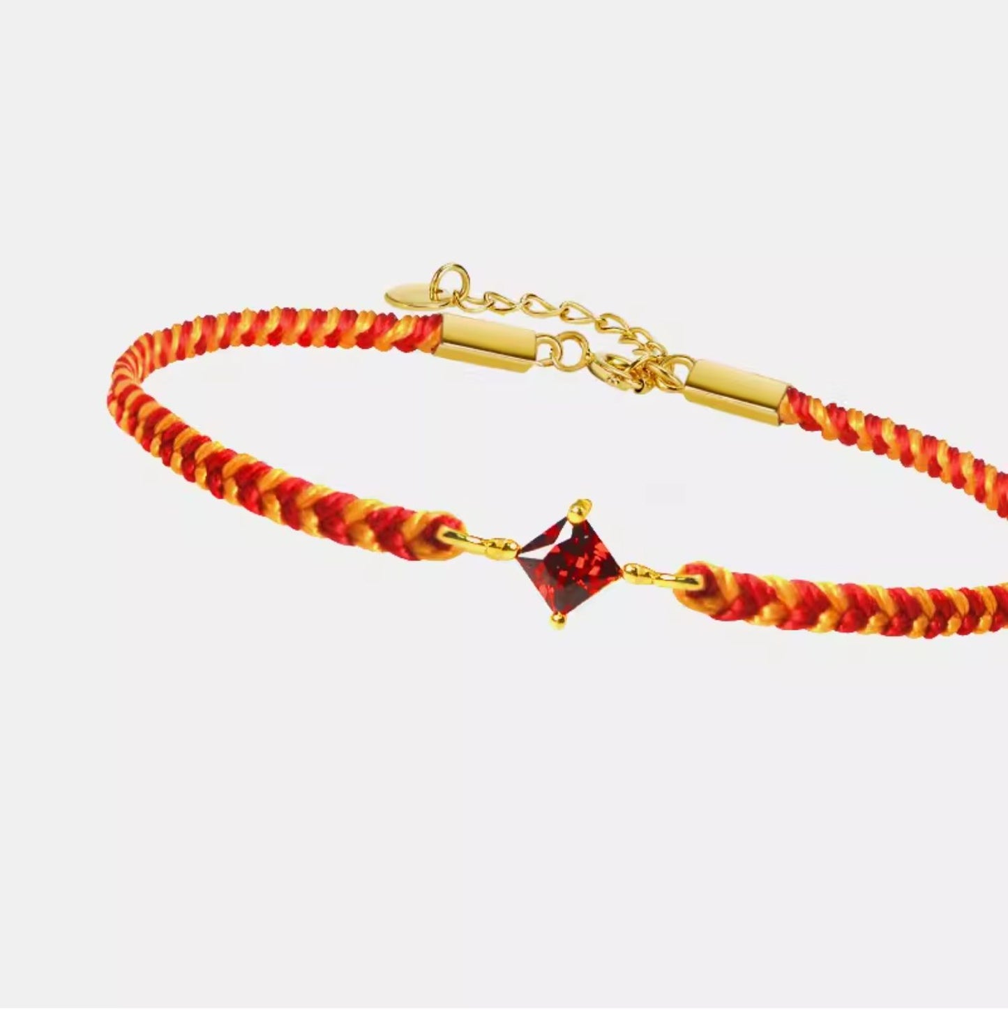 Bracelet with red and gold cord and a square gemstone on a white background