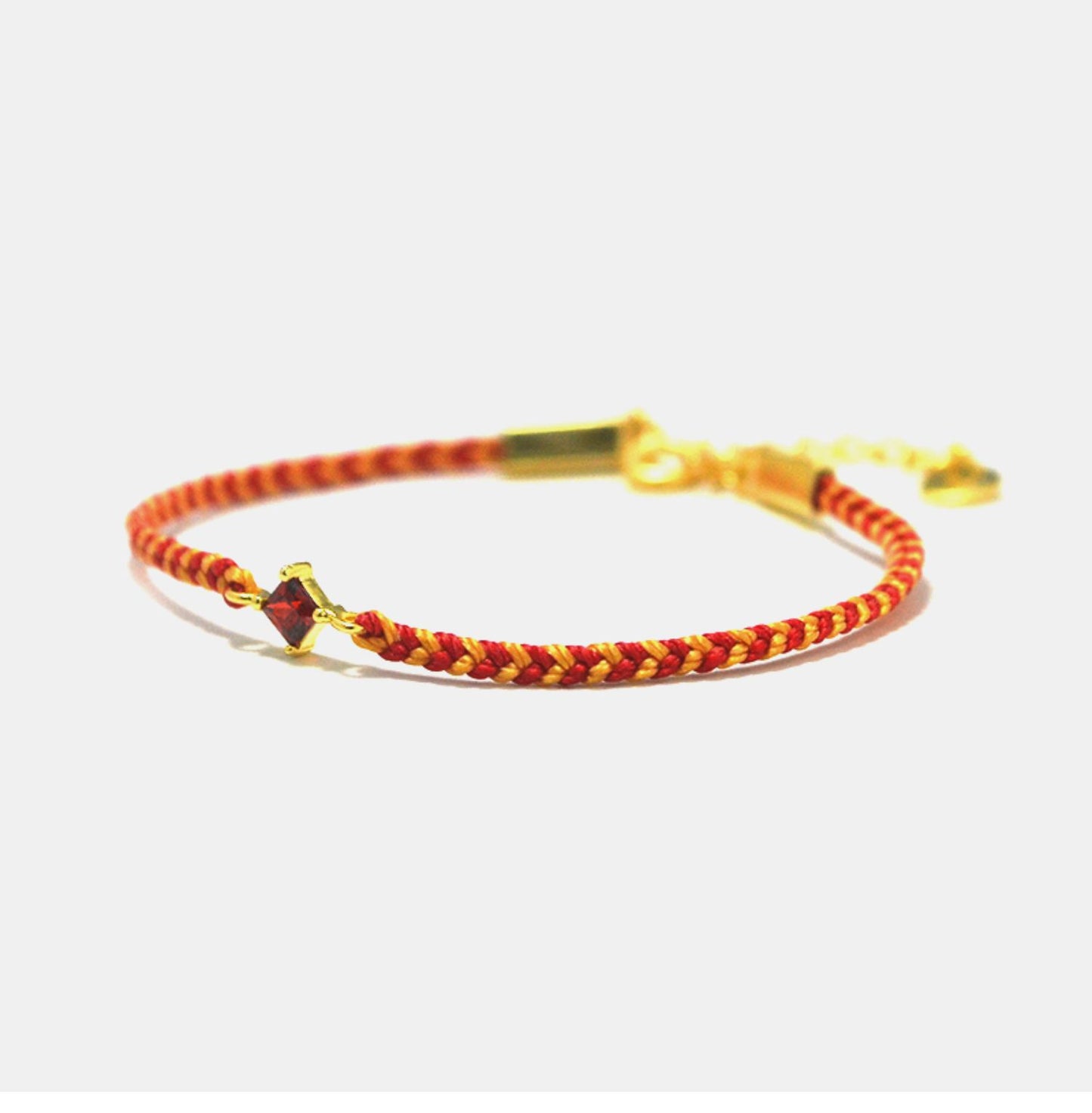 Bracelet with red and gold braided design on a white background