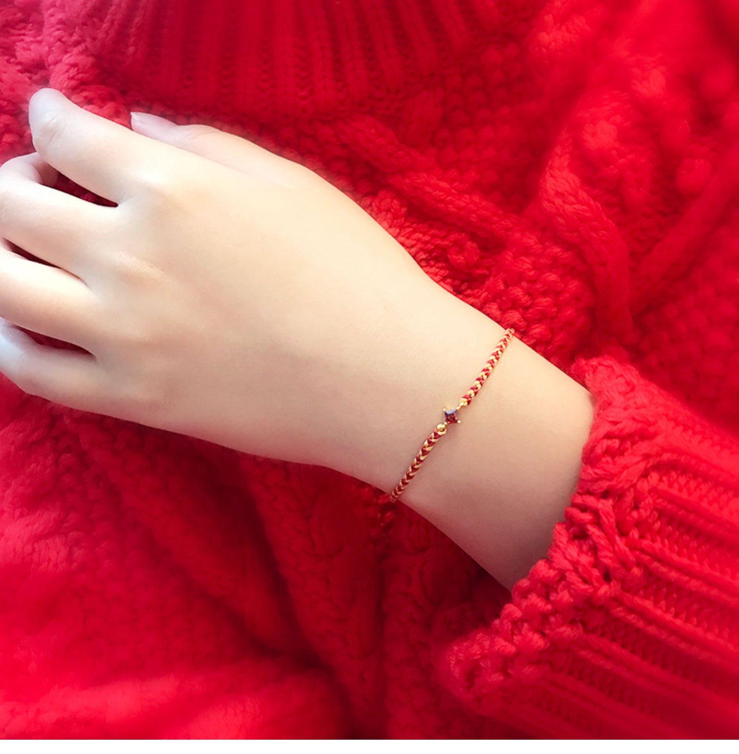 Hand wearing a red bracelet on a red textured fabric backgroundBracelet with red and gold braided design and a square gemstone on a white background
