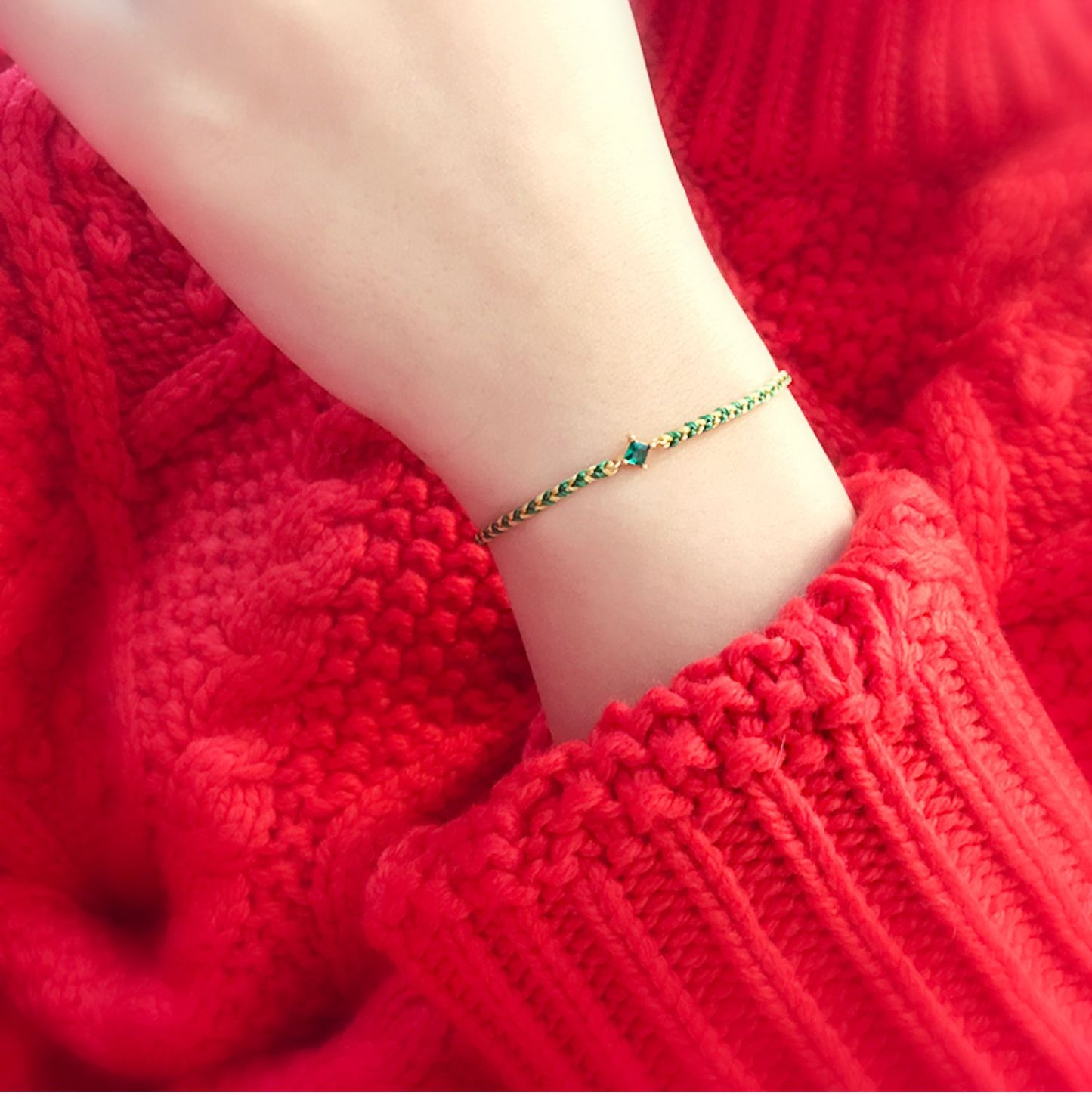 Close-up of a wrist wearing a green bracelet against a red textured fabric background