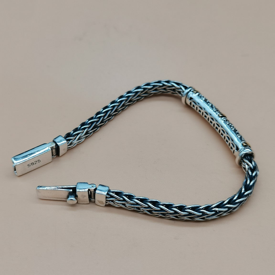 Silver braided bracelet on a beige background