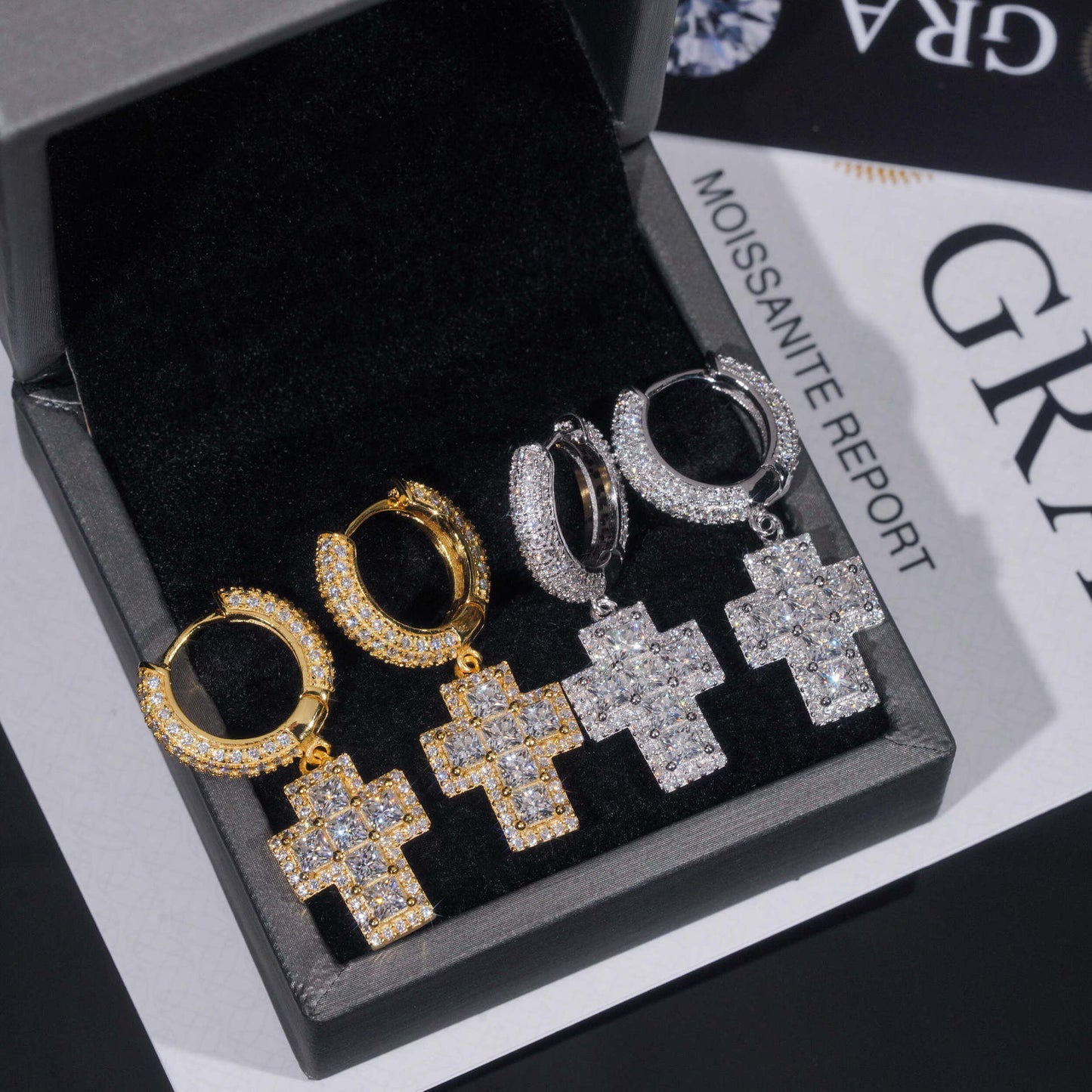 Gold and silver hoop earrings displayed in a jewelry box with a GIA moissanite report in the background.