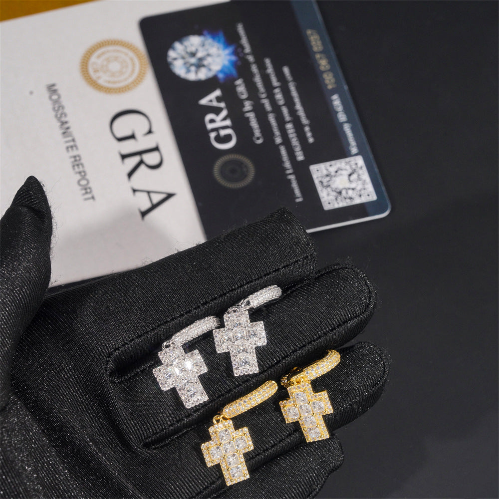 Gold and silver earrings on black gloves with a GRA diamond certification card in the background.