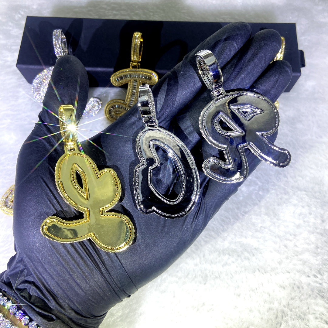 Gold and silver letter pendants on a white surface with a blue glove.