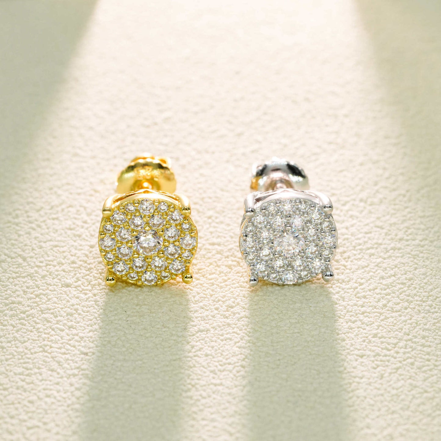 Gold and silver earrings with gemstones on a textured beige background