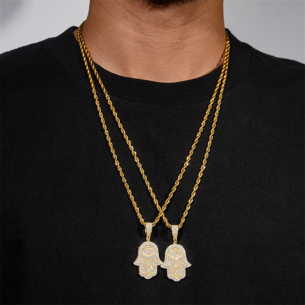 Two gold necklaces with Hamsa hand pendants on a black shirt.