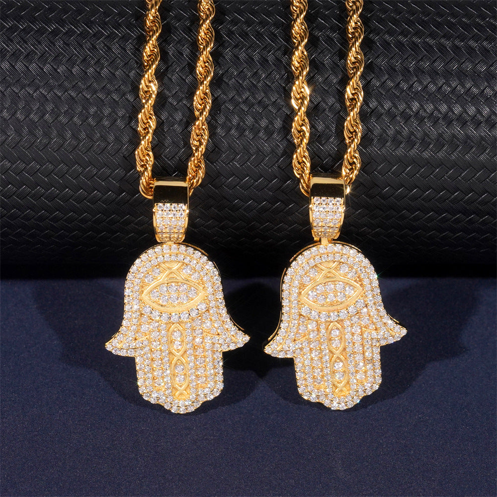 Two gold Hamsa hand pendants with chains on a dark textured background