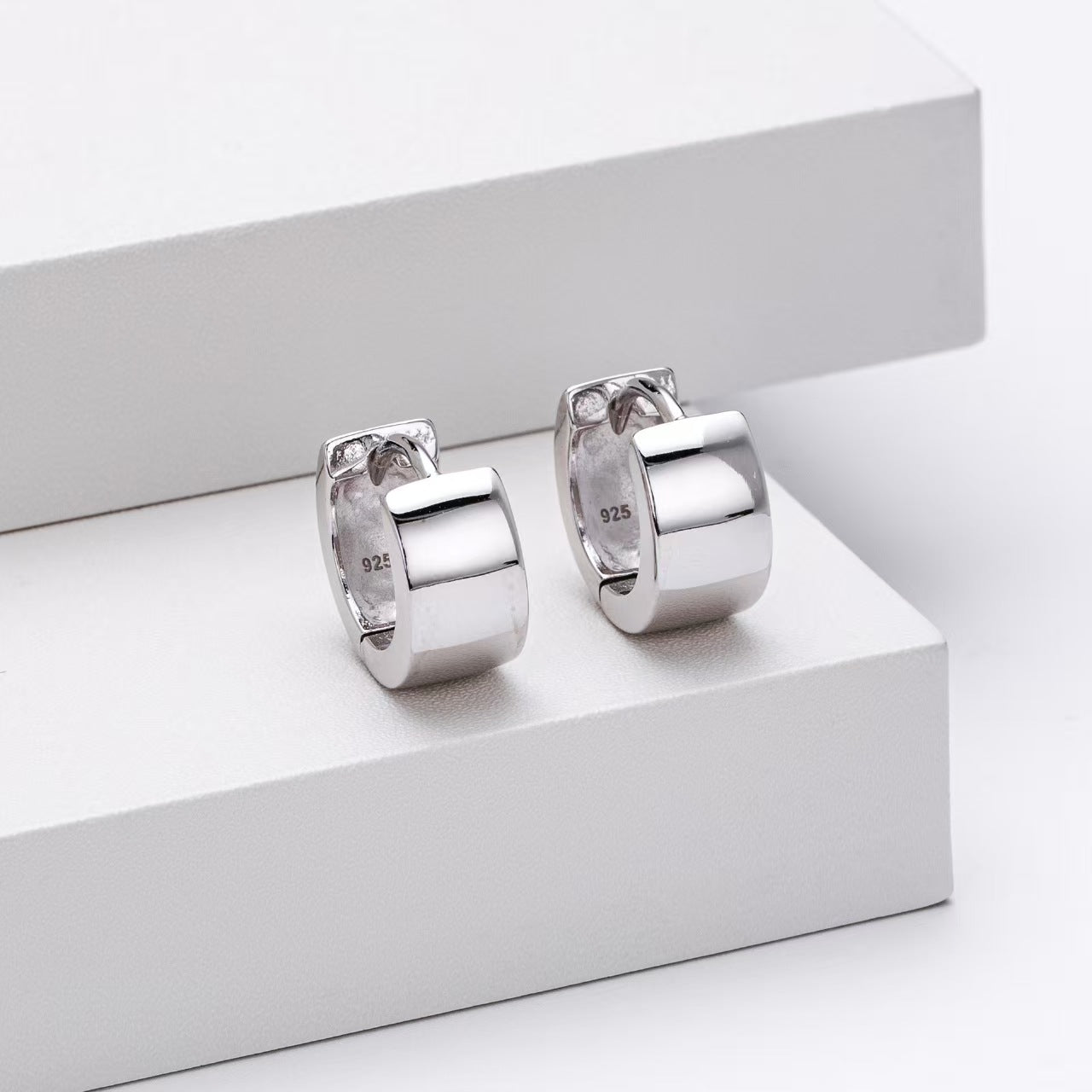Pair of silver hoop earrings on a white surface
